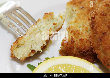 La morue panés délicieux fraîchement préparés Fishcakes avec citron et garnir de feuilles de salade isolé sur un fond blanc avec aucun peuple et un chemin de détourage Banque D'Images