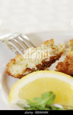 La morue panés délicieux fraîchement préparés Fishcakes avec citron et garnir de feuilles de salade isolé sur un fond blanc avec aucun peuple et un chemin de détourage Banque D'Images