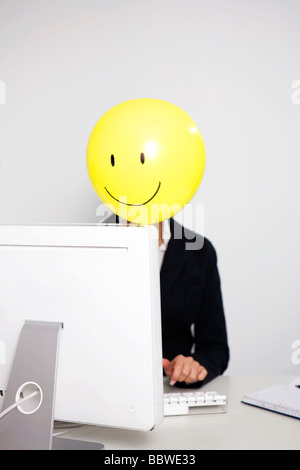 Femme avec ballon et en face de smiley face, in office Banque D'Images