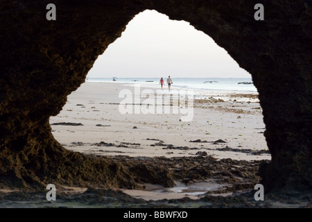 Couple walking on beach encadrée par cave - Diani Beach - près de Mombasa, Kenya Banque D'Images