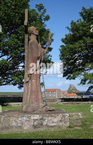 Statue de Saint Aidan sur Holy Island, Northumberland, Angleterre, avec Château de Lindisfarne en arrière-plan. Banque D'Images