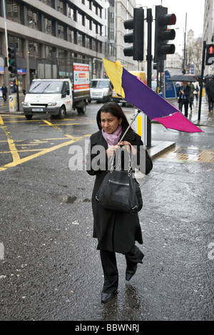 Une femme avec un parapluie retourné par un jour de vent à Londres Banque D'Images