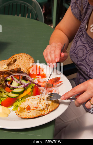 Une femme de manger une assiette de salade et un plat de fruits de mer crabe frais au Royaume-Uni à l'extérieur Banque D'Images