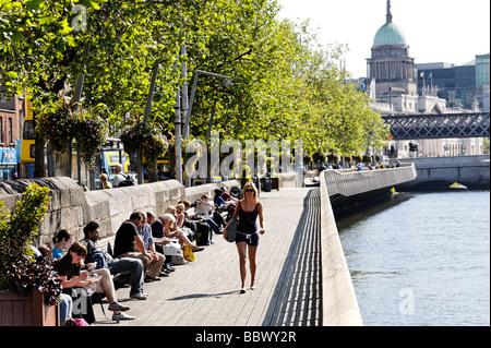 Les gens assis au soleil sur la Liffey boardwalk sur Lower Ormond Quay Centre de Dublin République d'Irlande Banque D'Images