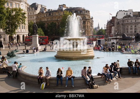 Se détendre autour de la fontaines de Trafalgar Square sur un après-midi de la fin de l'été, Londres, Angleterre. Banque D'Images