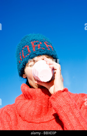 Une femme avec un chapeau bleu boire d'une tasse de la Suède. Banque D'Images