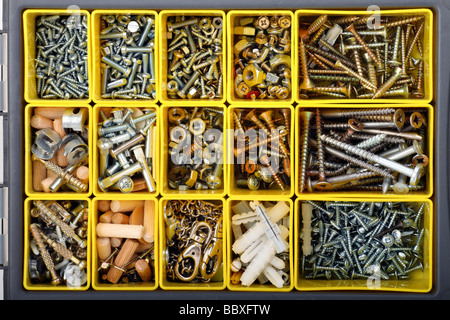 Vis, boulons, chevilles, écrous et autres trucs menuisier dans une boîte à outils en plastique jaune, vue du dessus Banque D'Images