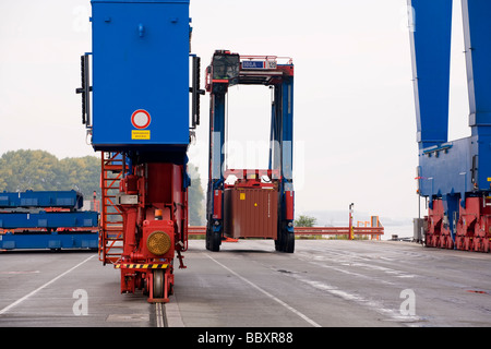 Un camion transporteur de chevauchement se déplace des conteneurs ISO de bornes à quai plus loin dans le terminal à conteneurs. Banque D'Images