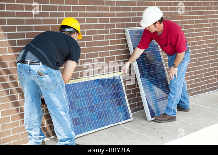 Electriciens mesurant les panneaux solaires avant de les installer Banque D'Images