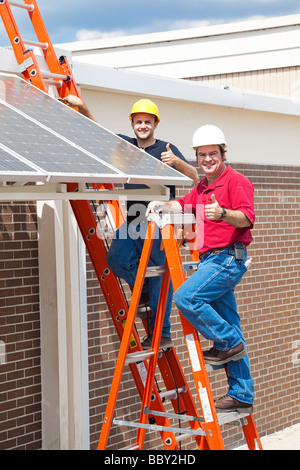 Deux travailleurs de l'installation des panneaux solaires et le pouce up sign Banque D'Images