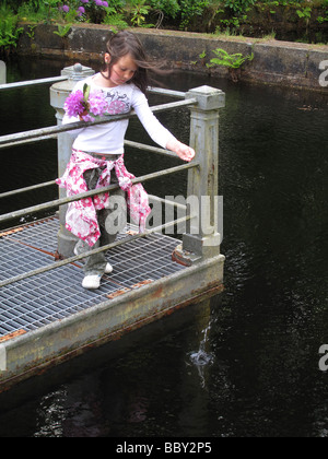 Enfant, à lancer de monnaie dans l'eau pour faire un voeu Banque D'Images