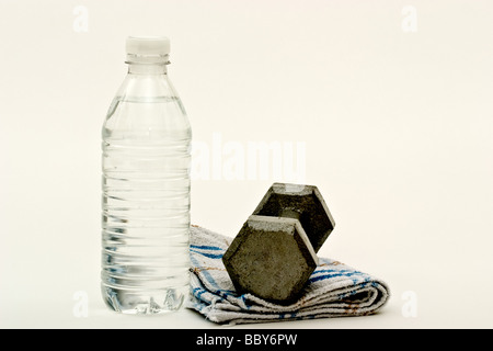 Un haltère sur une serviette de sueur à côté d'une bouteille d'eau Banque D'Images