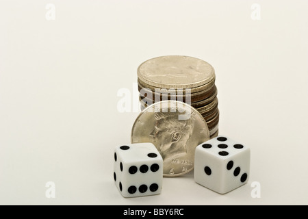Cubes de deux dés en face d'un tas de pièces en demi-dollar américain Banque D'Images