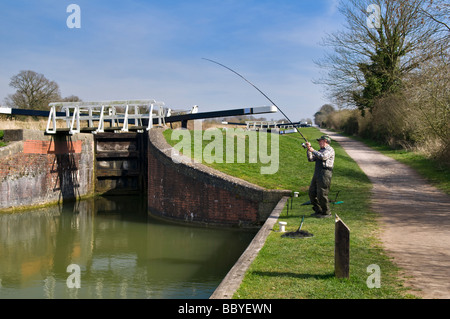Rembobinage pêcheur dans pike à la Kennet and Avon Canal, Devizes, Wiltshire sur journée ensoleillée au printemps Banque D'Images