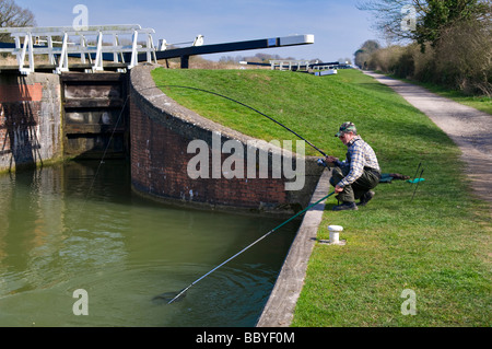 Rembobinage pêcheur dans pike à la Kennet and Avon Canal, Devizes, Wiltshire sur journée ensoleillée au printemps Banque D'Images