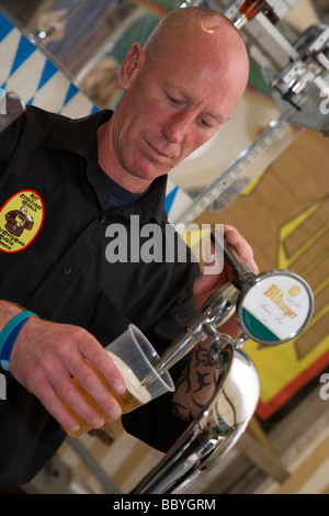 Verser la bière dans un barman une tasse en plastique dans une imitation de la bière allemande au Royaume-Uni Banque D'Images