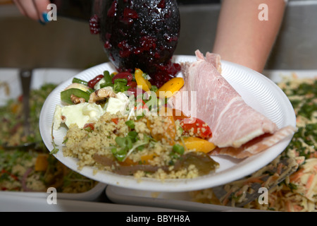 Vendeur femme plaçant divers articles salade de jambon sur une plaque de polystyrène à un marché d'alimentation au Royaume-Uni Banque D'Images