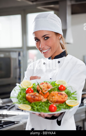 Femme chef montrant le plat et looking at camera Banque D'Images