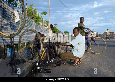 Les garçons l'exécution d'un atelier de réparation de bicyclettes dans les rues de Quelimane Mozambique Banque D'Images