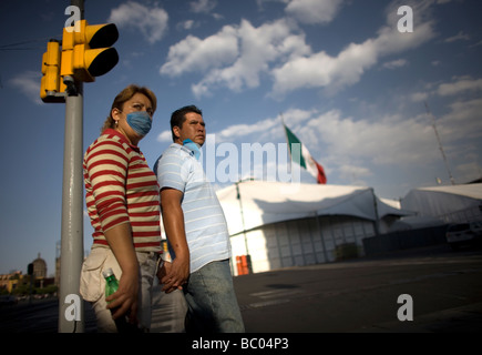 Un couple portant des masques par mesure de précaution contre la grippe porcine marche main dans la main dans la ville de Mexico's main place Zocalo. Banque D'Images