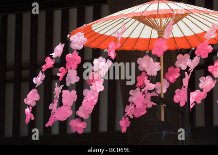Le souffle du vent de fleurs des cerisiers en fleur en plastique qui décorent un parapluie traditionnel pendant le festival du printemps de Takayama Banque D'Images