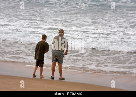 Apprendre à pêcher. Un garçon et son grand-père la pêche sur la plage de Hot Water Beach, péninsule de Coromandel, en Nouvelle-Zélande. Banque D'Images