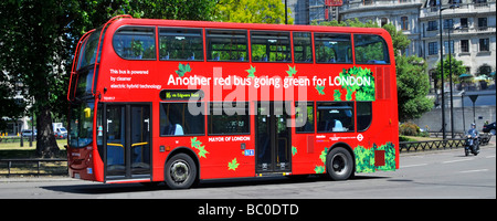 Vue latérale du bus à impériale rouge qui passe au vert Pour les transports en commun à Londres et équipés d'un aspirateur technologie hybride électrique Angleterre Royaume-Uni Banque D'Images