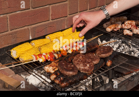 Close-up de saucisses, des hamburgers et du maïs et des kebabs par cuisson à l'extérieur à l'air libre sur un barbecue (BBQ) à l'été Banque D'Images