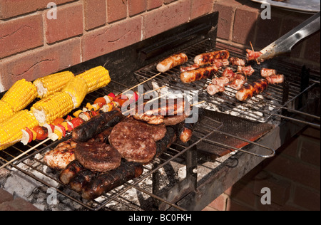 Close-up de saucisses, des hamburgers et du maïs et des kebabs par cuisson à l'extérieur à l'air libre sur un barbecue (BBQ) à l'été Banque D'Images