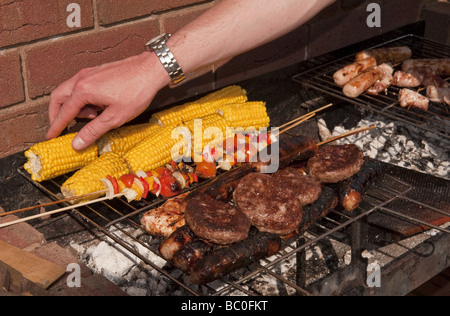 Close-up de saucisses, des hamburgers et du maïs et des kebabs par cuisson à l'extérieur à l'air libre sur un barbecue (BBQ) à l'été Banque D'Images