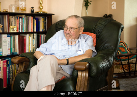 Vieil homme est assis dans son fauteuil préféré regarder la télévision Banque D'Images