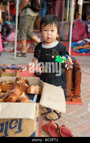 Un petit garçon Lao jouant sur ses parents à Luang Prabang de décrochage du marché touristique de nuit Banque D'Images