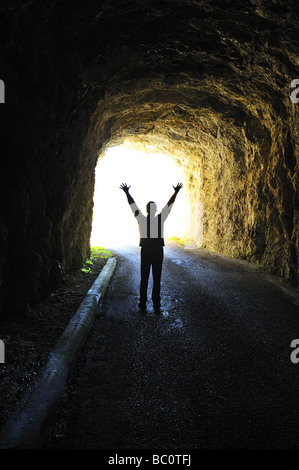 La lumière au bout du tunnel. Silhouette d'une figure debout à la fin d'un tunnel sombre à la recherche dans la lumière du jour. Banque D'Images