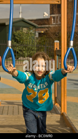 Garçon de se balancer sur les arceaux à une aire de jeux pour enfants dans le nord de Londres.jeux pour enfants Banque D'Images