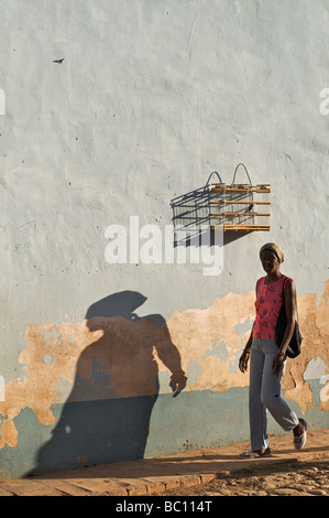 La femme cubaine en passant devant une cage à oiseaux, Trinidad, Cuba. Garder des oiseaux en cage est courante à Cuba Banque D'Images