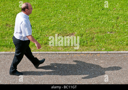 Homme marchant le long trottoir - France. Banque D'Images