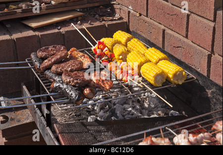 Close-up de saucisses, des hamburgers et du maïs et des kebabs par cuisson à l'extérieur à l'air libre sur un barbecue (BBQ) à l'été Banque D'Images