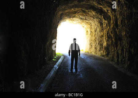 La lumière au bout du tunnel. Silhouette d'une figure debout à la fin d'un tunnel sombre à la recherche dans la lumière du jour. Banque D'Images