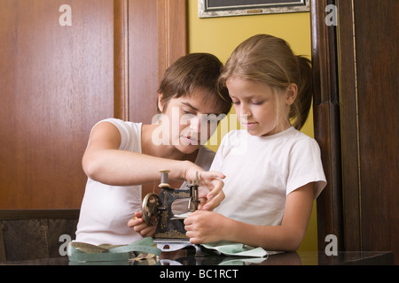 Mère et fille à l'aide de machine à coudre ancienne à l'accueil Banque D'Images