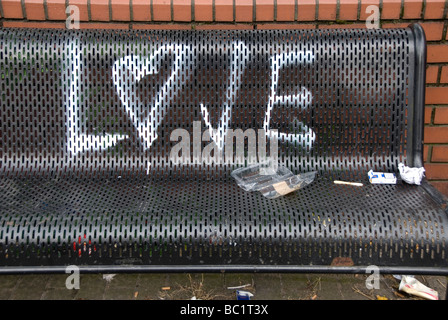 Amour graffitti sur un banc avec paquet de cigarettes jetées Belfast Banque D'Images