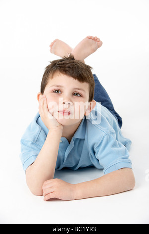 Young Boy Lying On Stomach In Studio Banque D'Images