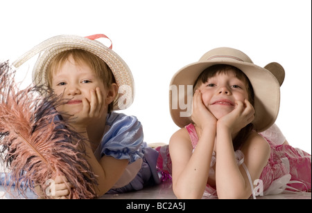 Magnifiques petites filles en robes et chapeaux se coucher sur le plancher isolé sur blanc Banque D'Images