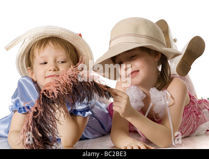 Magnifiques petites filles avec des robes en plumes et chapeaux à se coucher sur le plancher isolé sur blanc Banque D'Images