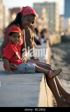 Jeune Cubaine femme avec enfant assis sur la digue au Malecon. La Havane, Cuba Banque D'Images