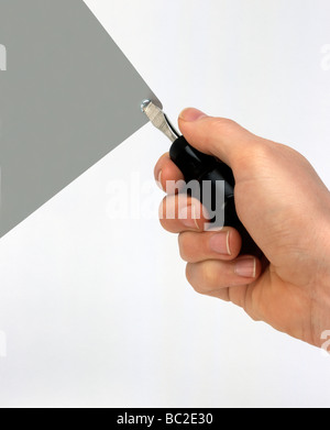 Main tenant un tournevis sur une plaque en aluminium Banque D'Images