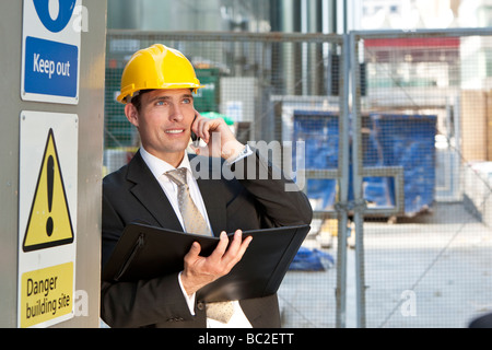 Gestionnaire d'un homme sur un site de construction portent un casque et à parler sur son téléphone Banque D'Images