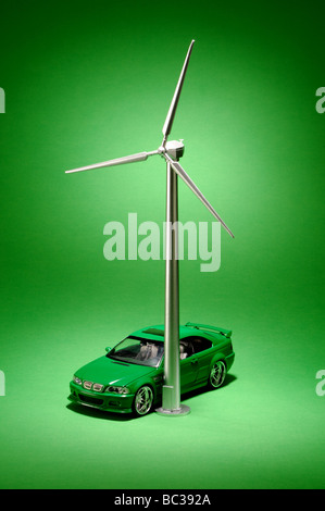 Une petite éolienne de métal sur un fond vert avec une petite voiture grren Banque D'Images