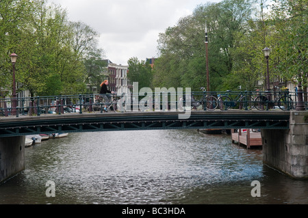 Cycliste femme traverse un pont sur le canal de Leidesgracht à Amsterdam Banque D'Images