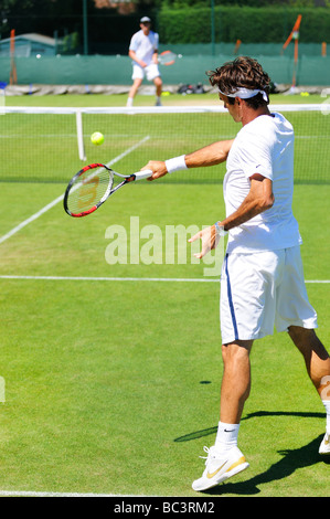 Le suisse Roger Federer joue avec Sam Querry sur une pratique du tribunal pendant le tournoi de Wimbledon 2009 Banque D'Images