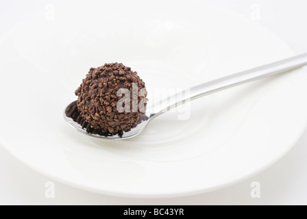 Truffe au chocolat sur une cuillère en argent et plaque blanche Banque D'Images